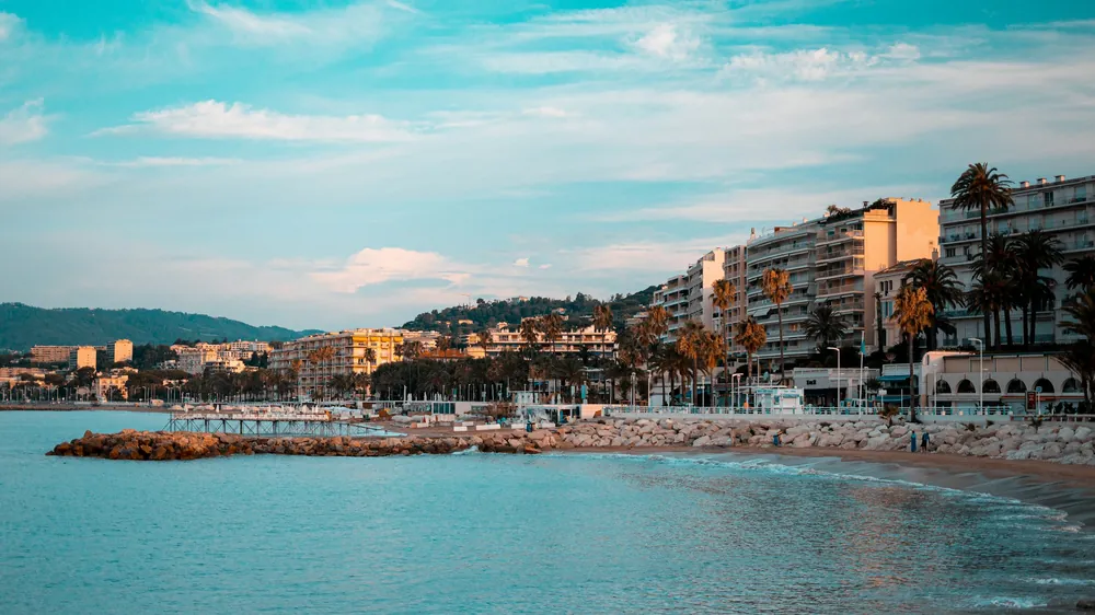 Il lungomare della Croisette a Cannes al tramonto con le palme e gli hotel sul mare