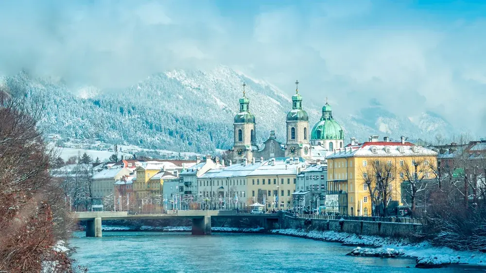 Il fiume Inn a Innsbruck con le cupole verdi del Duomo di San Giacomo e le Alpi innevate sullo sfondo