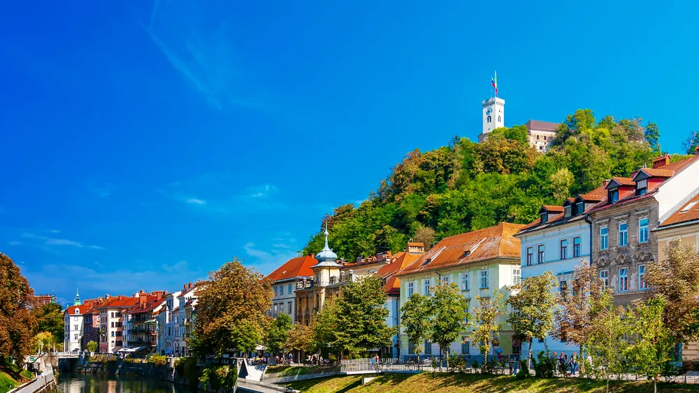 Il Castello di Lubiana sulla collina sopra le case colorate lungo il fiume Ljubljanica
